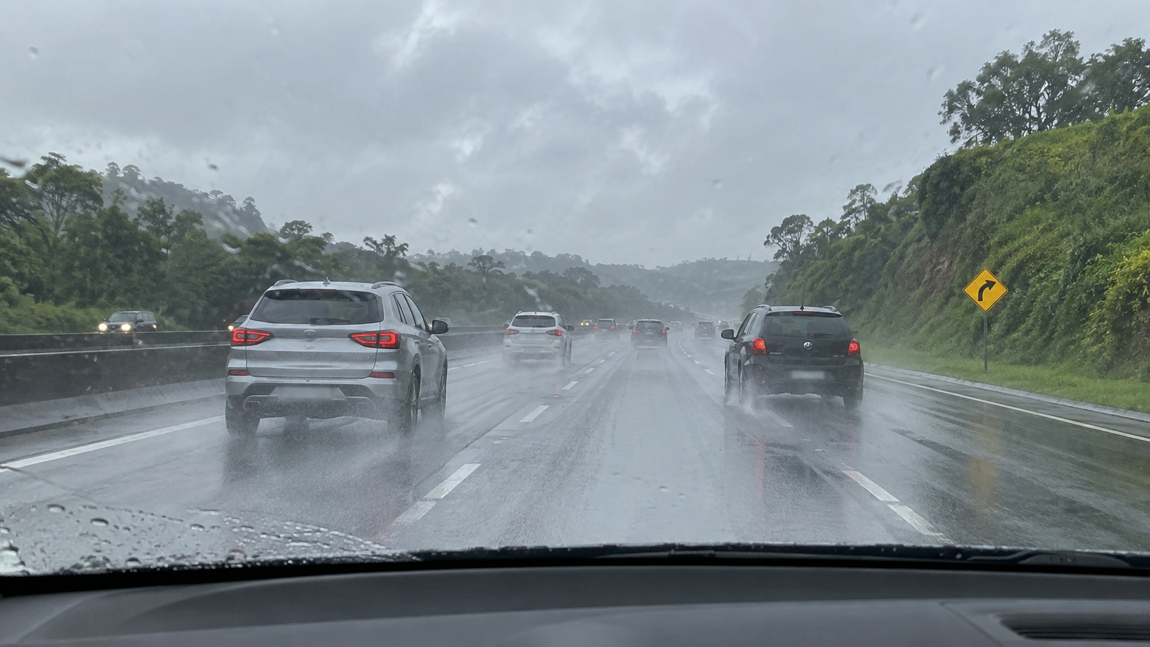 Veículos trafegam com cautela em rodovia molhada durante a chuva